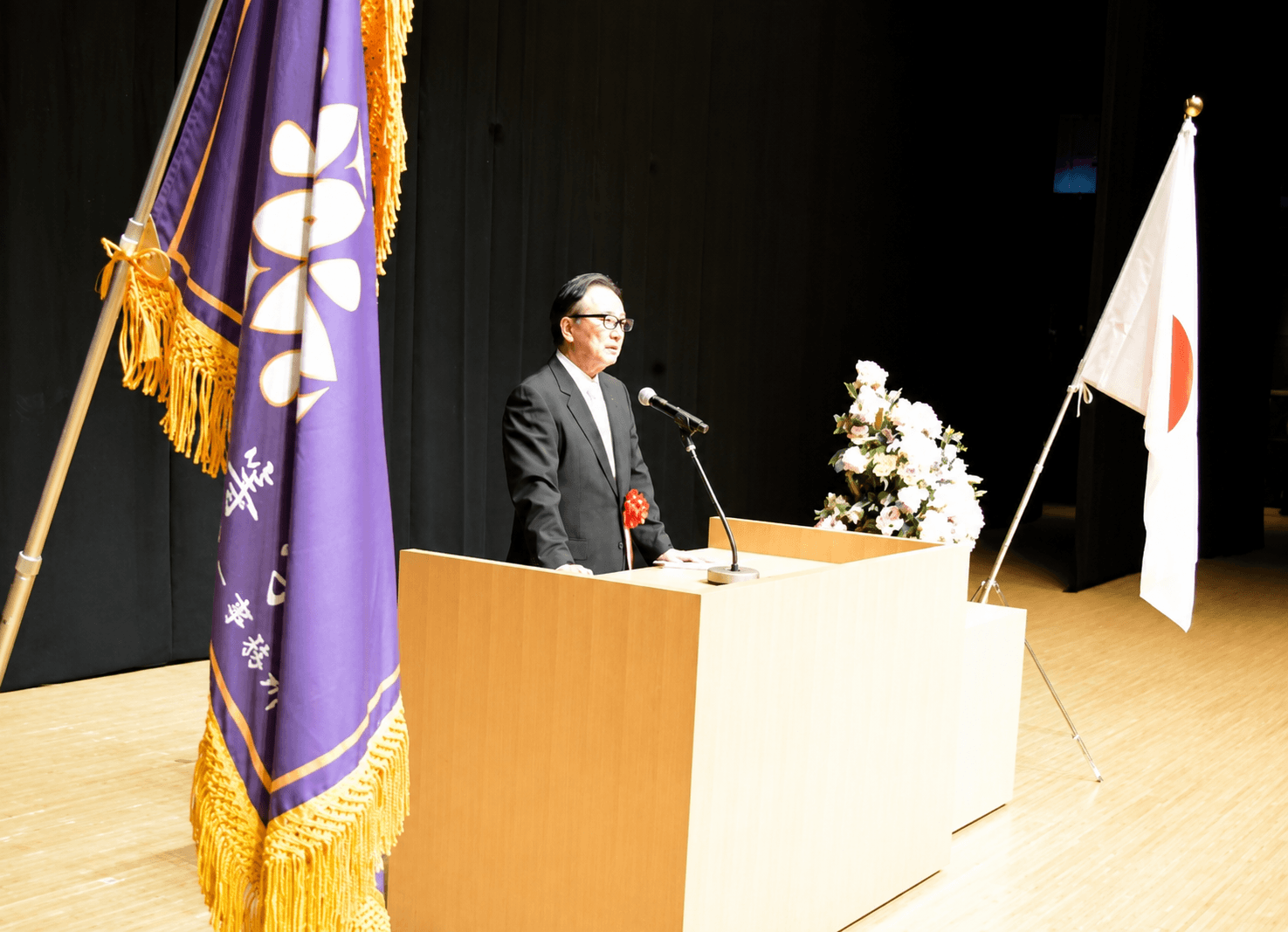 式典の演壇脇に掲げられた房付きの校旗（染め）と日章旗