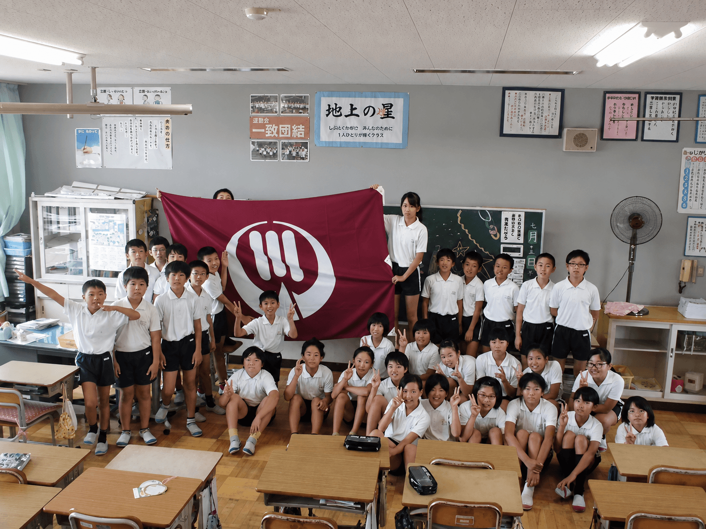 教室でクラス旗（校旗）を掲げる小学生たち